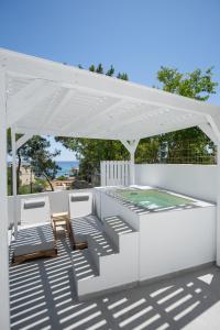 a white pergola with two chairs and a table at Theros Luxury Apartment in Archangelos