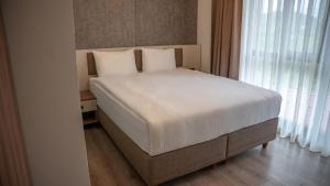 a bedroom with a bed with white sheets and a window at Santana Suıts in Trabzon