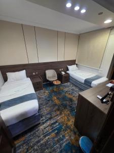 a hotel room with two beds and a desk at فندق مواسم الخير in Al ‘Azīzīyah