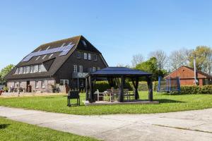 a gazebo in front of a large building at Ferien- und Pferdehof Egelkraut "Feriendomizil am Meer" in Wangerland