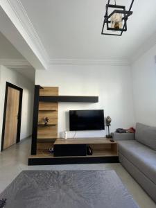 a living room with a couch and a flat screen tv at Complex riad tanger in Hajreien