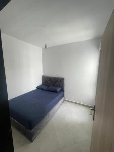 a bedroom with a blue bed in a white room at Complex riad tanger in Hajreien