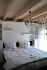 a bedroom with a large white bed with a chandelier at Vakantiehuis Olivia in Schoorl
