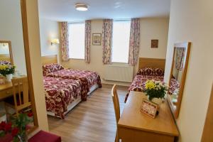 a hotel room with a bed and a table with a mirror at St Winefride's Guesthouse in Holywell +28 photos
