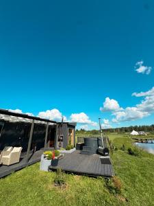 a house with a deck and a lake at Retrīts MIGLA with sauna included in Stacija )) (( Blukas