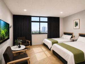 a hotel room with two beds and a window at 礁溪希沐湯泉民宿 2026年7月全新面貌登場 價格優惠中 in Jiaoxi