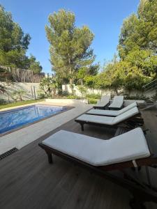 two lounge chairs and a pool in a yard at Wonderful Villa Cala Tarida in Sant Josep de sa Talaia