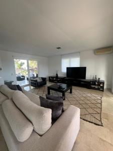 a living room with a couch and a flat screen tv at Wonderful Villa Cala Tarida in Sant Josep de sa Talaia