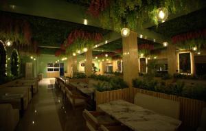 a restaurant with tables and chairs and plants at Tiger Aura Resort in Rāmnagar