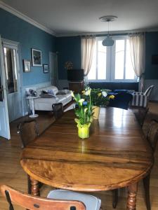 a dining room with a wooden table and a living room at Augustodun'Home in Autun
