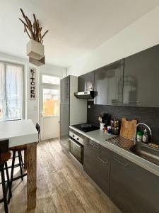 a kitchen with stainless steel appliances and a table at La Maison Du Bois Flotté in Boulogne-sur-Mer