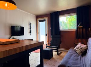 a room with a desk and a chair and a television at Attitude Montagne in Saint Adolphe D'Howard