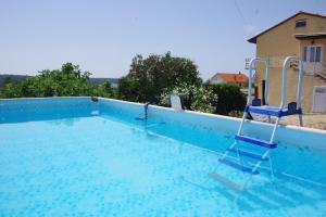 a blue swimming pool with two chairs in it at One Bedroom Apartment in Banjol