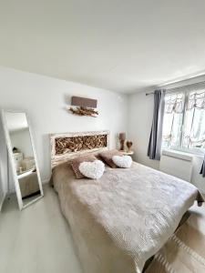 a white bedroom with a large bed with two pillows at La Maison Du Bois Flotté in Boulogne-sur-Mer