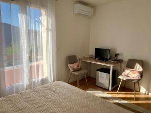 a bedroom with a bed and a desk with a computer at Villa Câline chambres d'hôtes in Vesseaux