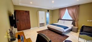 a bedroom with a bed and a chair and a table at Ridge Condos Hotel - Phase Three in Kumasi