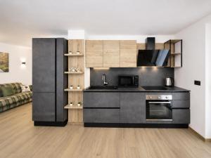 a kitchen with a black refrigerator and a living room at MOUNTAIN HOME Fiemme - Nuovo, Balconi e Garage in Castello di Fiemme