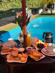Ein Tisch voller Teller mit Essen neben einem Pool in der Unterkunft Hotel Suites Bambú in Minga Guazú