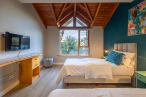 ein Schlafzimmer mit Bett, Fernseher und Fenster in der Unterkunft Peninsula Petit in San Carlos de Bariloche