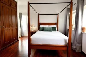 a bedroom with a canopy bed with white sheets and green pillows at Casa do Sol Wellness Villa in Óbidos