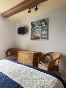 a bedroom with a bed and two chairs and a tv at Les bon bois in Germignac