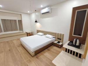 a bedroom with a white bed and a window at Hotel Krishiv- Sanand in Sānand