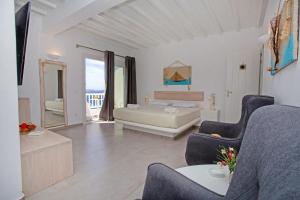 a living room with a bed and a couch and chairs at Aegean View Suites Mykonos in Agios Stefanos