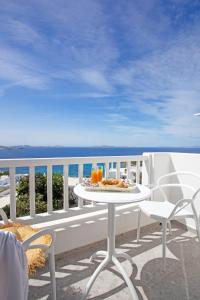 a white table and chairs on a balcony with the ocean at Aegean View Suites Mykonos in Agios Stefanos