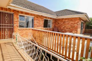 a brick house with a wooden railing on a balcony at Magna Apartment in Jeffreys Bay