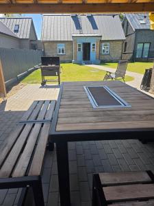a wooden picnic table with a bench on a patio at Dzintarielas Miera Osta in Pāvilosta