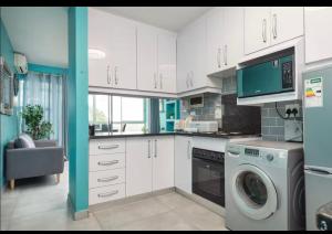 a kitchen with white cabinets and a washing machine at 94 Camarque Umdloti in Umdloti