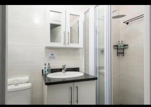 a white bathroom with a sink and a shower at 94 Camarque Umdloti in Umdloti +10 photos