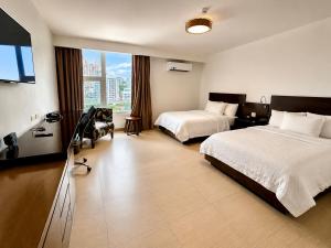 a hotel room with two beds and a flat screen tv at The District Hotel in Panama City +16 photos