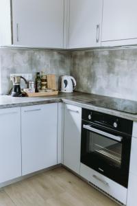 a kitchen with white cabinets and a black oven at Obsenieki - moderna lauku sēta in Stalidzāni +20 photos