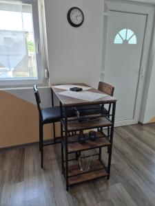 a table and a chair in a room with a clock on the wall at Auszeit in Balatonmagyaród +10 photos