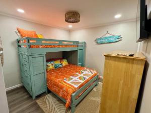 a bedroom with a bunk bed with an orange bedspread at Caribbean LYMM Cottage in Carolina Beach
