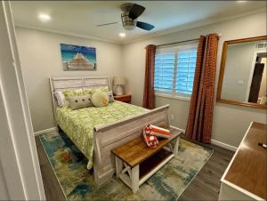 a bedroom with a bed and a table and a window at Caribbean LYMM Cottage in Carolina Beach