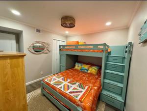 a bedroom with a bunk bed with an orange bedspread at Caribbean LYMM Cottage in Carolina Beach +19 photos
