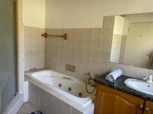 a bathroom with a bath tub and a sink at Shamwari Guesthouse in Kalkheuvel