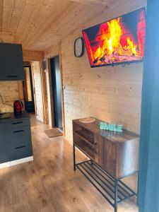 a living room with a fireplace and a tv on the wall at By The Lake - Domki I Sauna Nad Jeziorem in Załęże