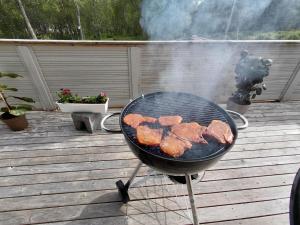 a grill with meat cooking on a deck at Artic home komfort in Tromsø