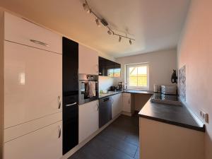 a kitchen with white cabinets and black appliances at Ferienwohnungen Hopfenhaus in Spalt