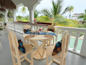 a dining room with a table and chairs on a balcony at Bahari Paje Beach House in Paje
