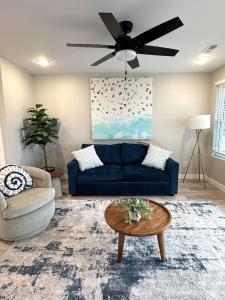 a living room with a blue couch and a ceiling fan at Lake of the Ozarks Waterfront Kapilana Resort Condos - Pool, Dock, Grill, Boat Rentals Fishing & Lake Views in Osage Beach