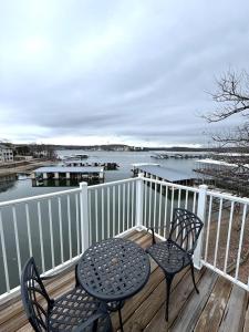 two chairs and a table on a deck with the water at Lake of the Ozarks Waterfront Kapilana Resort Condos - Pool, Dock, Grill, Boat Rentals Fishing & Lake Views in Osage Beach +40 photos