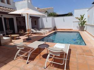 a pool with chairs and a table and an umbrella at Villa Mara Valle Golf Resort in Murcia