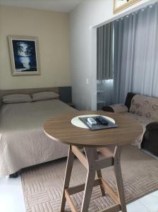 a room with a bed and a wooden table with a bed and a table at Flat Vista do Cruzeiro in Jacobina