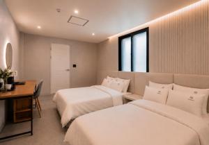 a hotel room with two beds and a desk and a desk at Busan Station Iruda Hotel in Busan