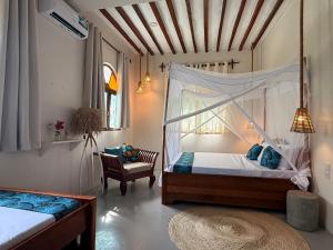 a bedroom with a canopy bed and a chair at Bahari Paje Beach House in Paje
