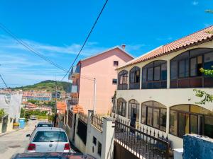 a car parked in front of a pink building at London Guest House in Caneças